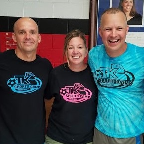 Three camp staff members pose together, wearing matching shirts for TK Sports Camp. Their smiles convey a welcoming and energetic atmosphere.